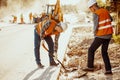 Workers in reflective vests using shovels during carriageway work Royalty Free Stock Photo