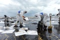 Workers remove and clean up crude oil spilled with absorbent pap