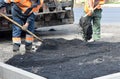 Workers repair the road throws asphalt with a shovel. Royalty Free Stock Photo