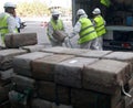 Workers retrieve drug packs from a truck before its destruction