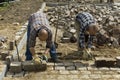 Workers: road builders laying cobblestones