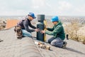 workers on the roof installing tin cap on the iron chimney