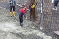 Workers in rubber boots pouring concrete