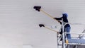 2 workers on scaffolding using flat wet mops to cleaning white ceiling of petrol station Royalty Free Stock Photo