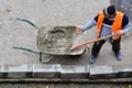 Workers shovel wet concrete from wheelbarrow