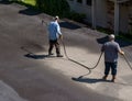 Workers spraying blacktop or asphalt sealer onto roadway