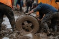 Workers struggle to remove a stuck wheel from muddy terrain during a challenging recovery operation