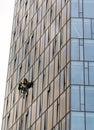 Workers suspended on ropes repairing glass building