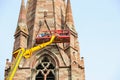 Workers on tall lifting platform repairing the church facade