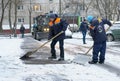 Workers in uniform with big shovels, a tractor removes snow from the road. Snow removal on the city streets Royalty Free Stock Photo