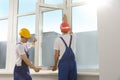Workers in uniform installing plastic window indoors Royalty Free Stock Photo