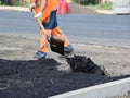 Workers in uniform throw shovels of asphalt on the road. Royalty Free Stock Photo