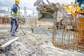 Workers are unloading concrete with shovel from excavator`s fron