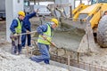 Workers are unloading concrete with shovel from excavator`s fron