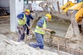 Workers are unloading concrete with shovel from excavator`s fron