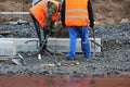 Workers use a carrying tool to level and install concrete curbs. Installing a concrete curb at the edge of a sidewalk