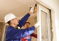 Workers using electric screwdriver for window installation