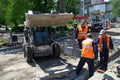 Workers using a mini backhoe loader establish a curb at the crossroads of city streets. May 29, 2020, Russia, Magnitogorsk Royalty Free Stock Photo
