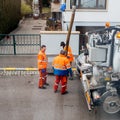 workers using sewerage truck and large pipe working on the clogged street rain water