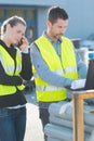 workers wearing high-visibility vests using laptop and smartphone outdoors