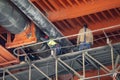 Workers welding district heating pipeline under metal bridge