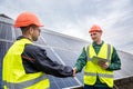 Workers in work clothes greet each other by the hand before starting work on solar panels. Royalty Free Stock Photo