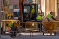 Workers working on public works in a street in Granollers. Protection fences and backhoe. Passersby walking. Concrete mixer Royalty Free Stock Photo
