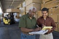 Workers Writing On Clipboard With Man Driving Forktruck In The Background Royalty Free Stock Photo