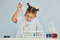 Workes with liquid that is in test tubes. Little girl in coat playing a scientist in lab by using equipment Royalty Free Stock Photo