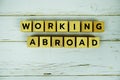 Working Abroad with wooden blocks alphabet letters on wooden background Royalty Free Stock Photo
