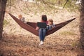 Working away from office concept, woman with two kids working on laptop while lying in hammock in a forest Royalty Free Stock Photo