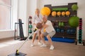 Grey-haired male patient having a workout with a ball in rehabilitation center with a female instructor Royalty Free Stock Photo