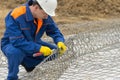 Working in a blue uniform, knit mesh for cells under the stones to improve the shore, close-up