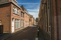 Working-class brick houses in a narrow empty street under sunny blue sky at Weesp.