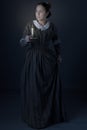 A working class Victorian woman holding a candle in the dark against a grey studio backdrop Royalty Free Stock Photo