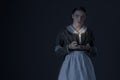 A working class Victorian woman wearing a dark green check bodice and skirt with an apron and holding a candle. Royalty Free Stock Photo