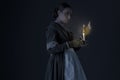 A working class Victorian woman wearing a dark green check bodice and skirt with an apron and holding a candle. Royalty Free Stock Photo