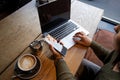 Working in a coffee shop. Casual looking young woman works on laptop in coffeehouse. She touches touchpad with on hand Royalty Free Stock Photo