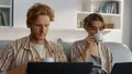 Working couple drinking coffee at home office closeup. Freelancers look laptops