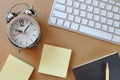 Working desk with alarm clock, keyboard, sticky note, book and pencil Royalty Free Stock Photo