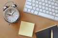 Working desk with alarm clock, keyboard, sticky note, book and pencil Royalty Free Stock Photo