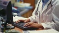 Working efficiently a physician assistant calmly types away at their computer while also managing paperwork and charts