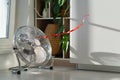 Electric fan with red wriggle ribbon designed to cool air and supply wind located near window