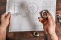 The working engineer holds a bevel gear in his hand against the background of a technical drawing Royalty Free Stock Photo