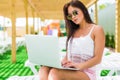 Working even on vacation. Attractive young woman in sunglasses and hat is lying on a chaise-longue near swimming pool with laptop. Royalty Free Stock Photo