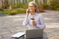 Working from everywhere. Portrait of a happy beautiful mature business woman drinking coffee and talking with on mobile Royalty Free Stock Photo