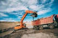 Working excavator on site, loading dumper truck during earthmoving works Royalty Free Stock Photo