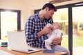 Working Father Using Laptop At Home Whilst Feeding Baby Son On Knee With Bottle Royalty Free Stock Photo