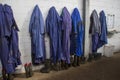 Working form of livestock farm workers in the Netherlands is a blue uniform and rubber boots. The form hangs in a row on a hanger Royalty Free Stock Photo