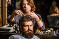 Working hair scissors. Professional barber girl cutting hair of bearded man. He is getting haircut at barbershop Royalty Free Stock Photo